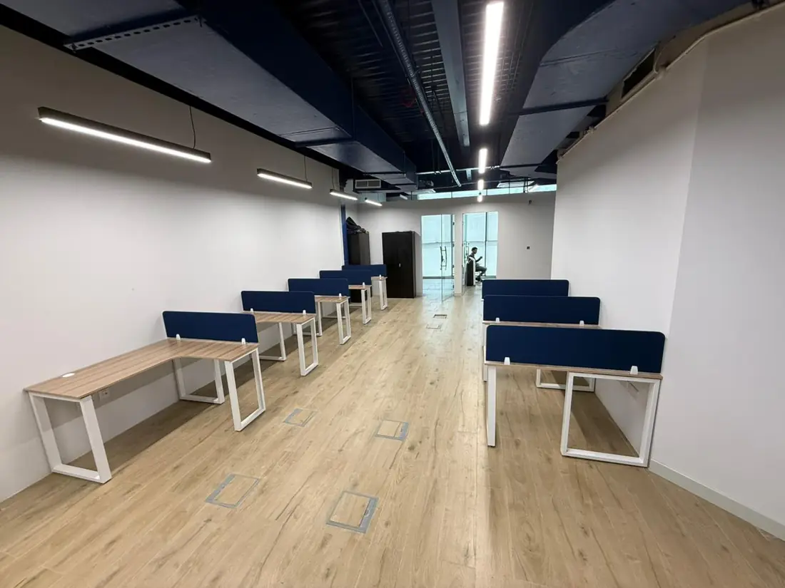 Long white desking with navy screens along a corridor